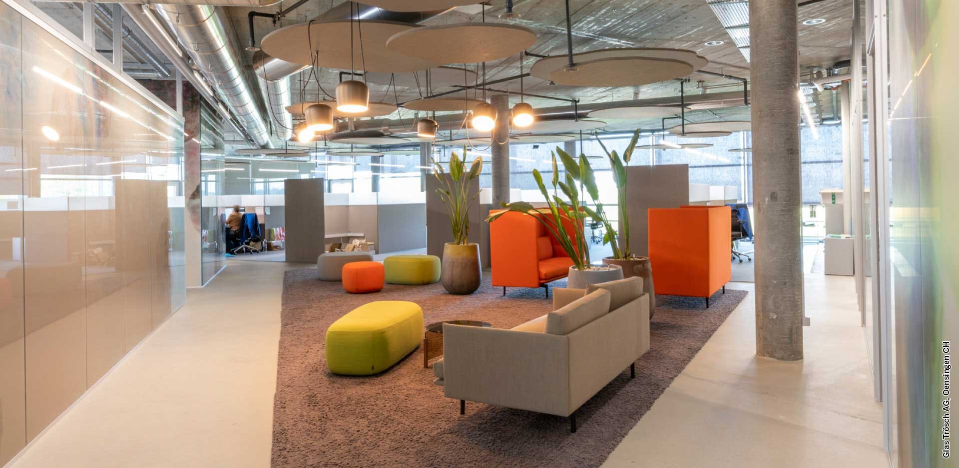 A community space in an office setting, featuring seating options and sound-absorbing panels
