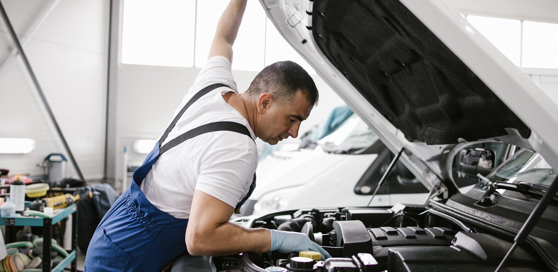 Mann betrachtet den Motorraum eines Autos 