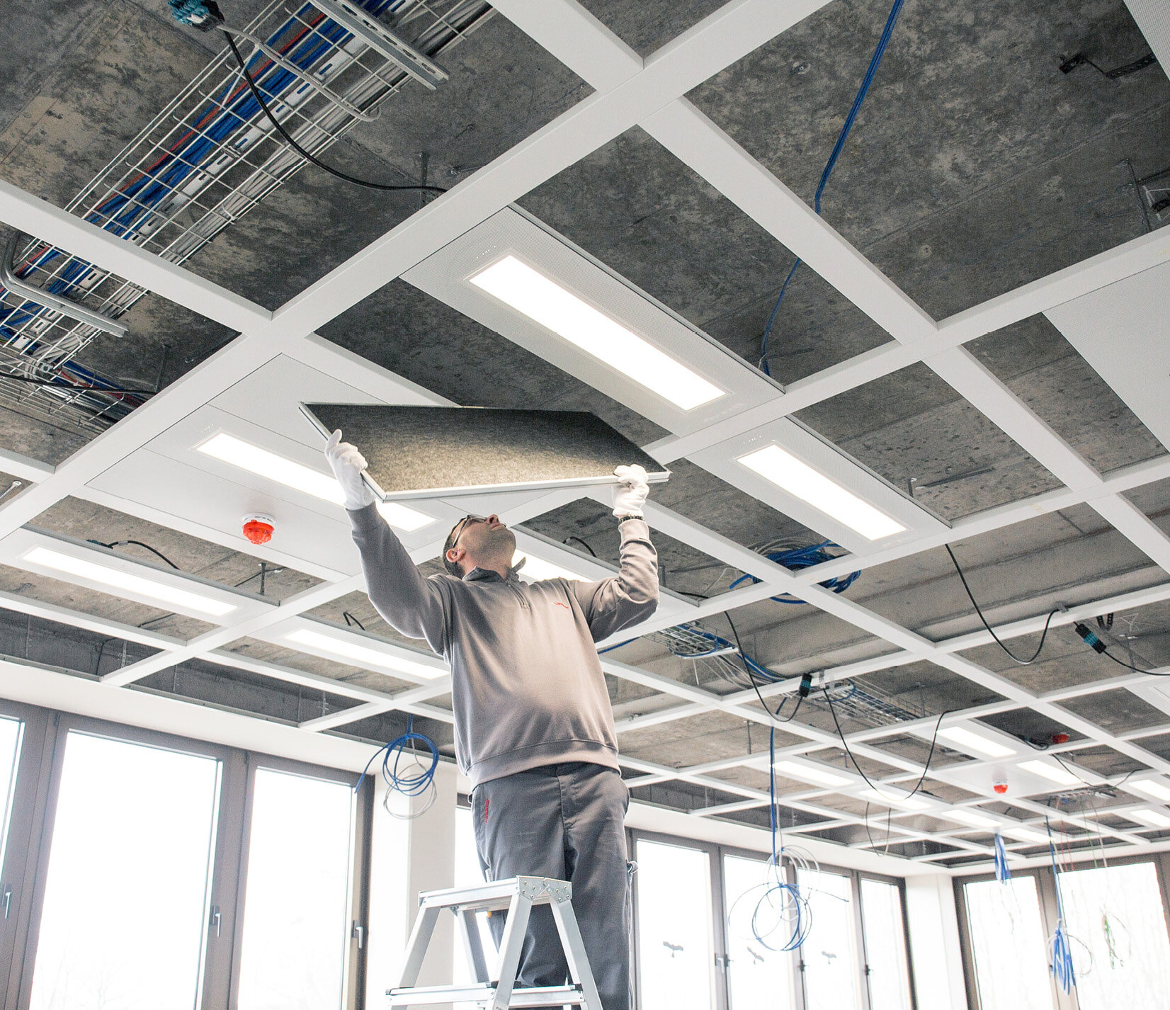 Ein Arbeiter auf einer Baustelle beim Einbau der Deckendämmung | Sandler Group