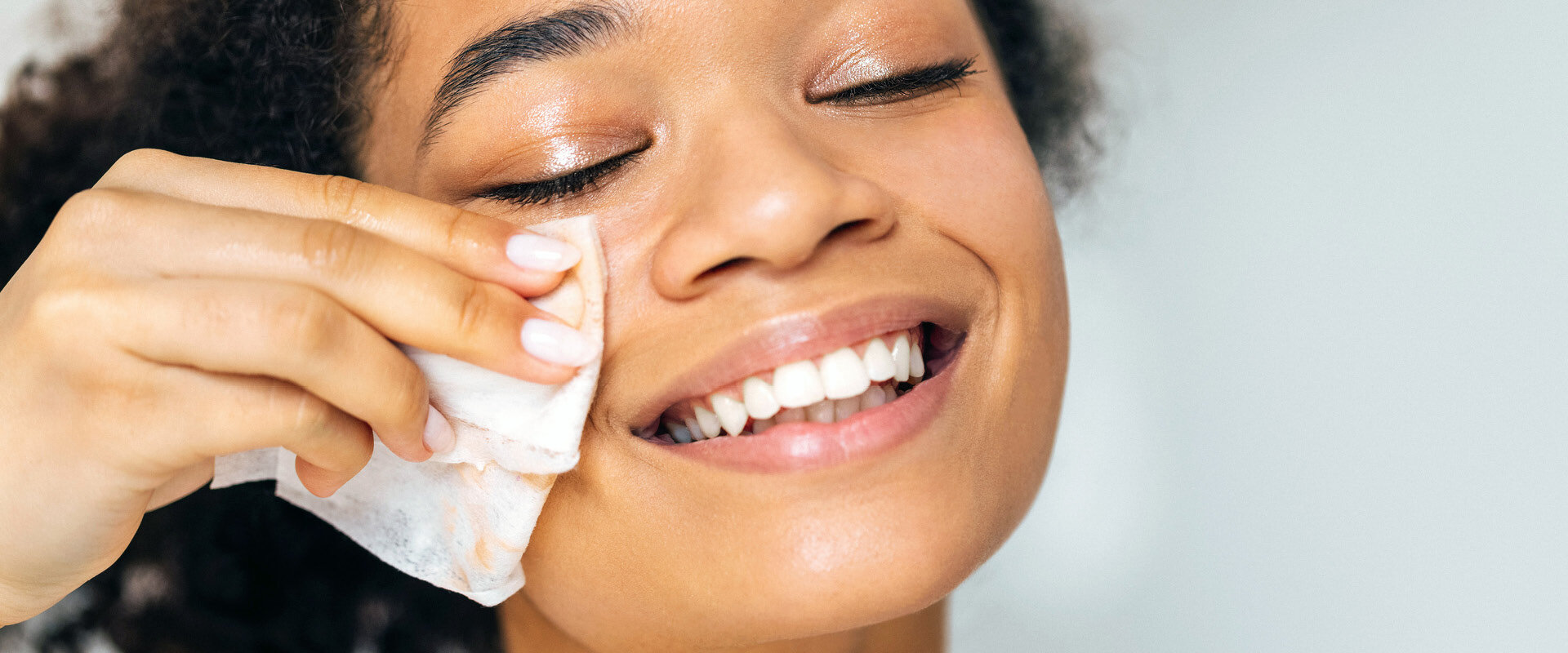 Frau, die ihr Gesicht mit einem Wipe aus Vliesstoff reinigt