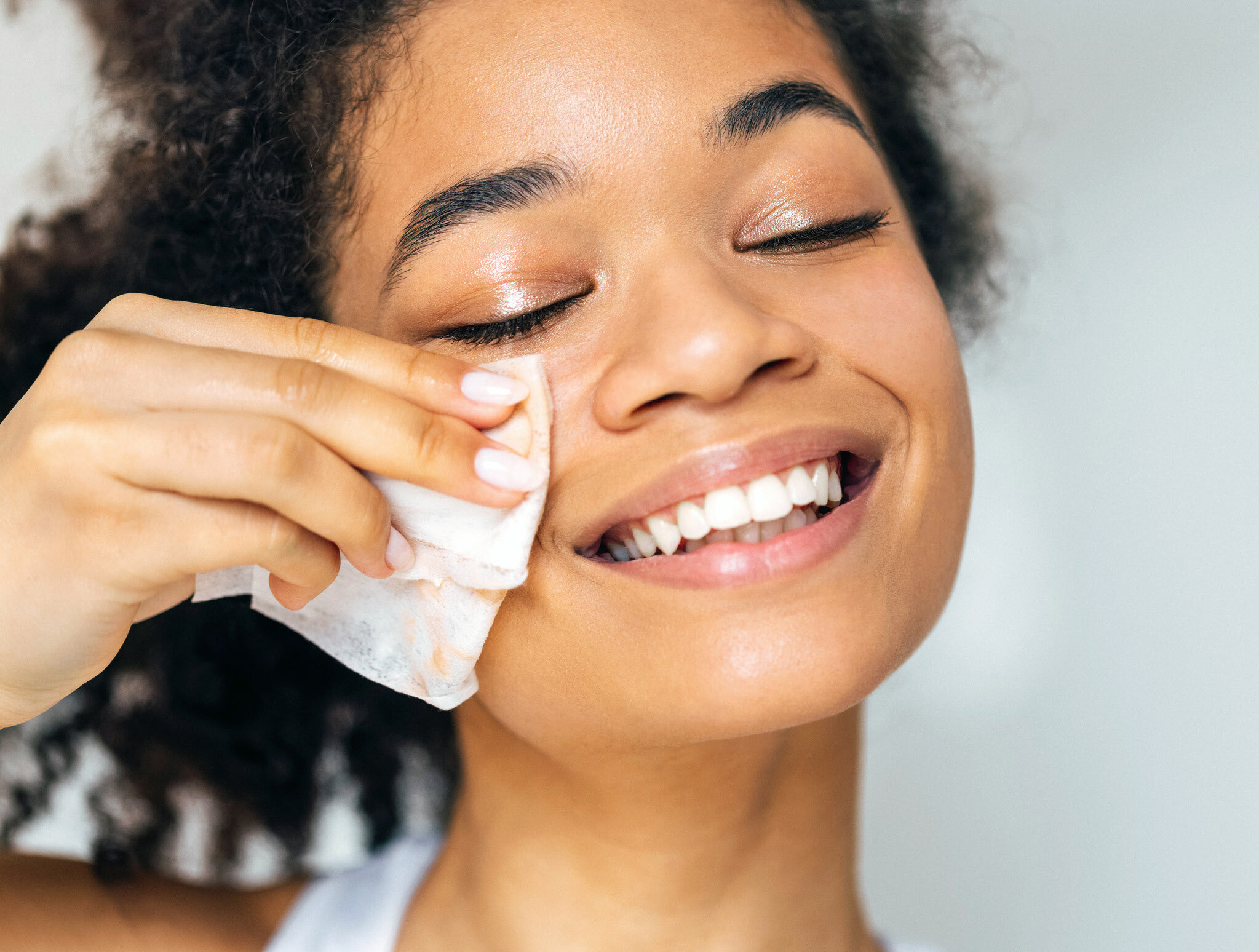 Frau, die ihr Gesicht mit einem Abschminktuch/Cleaning Wipe reinigt