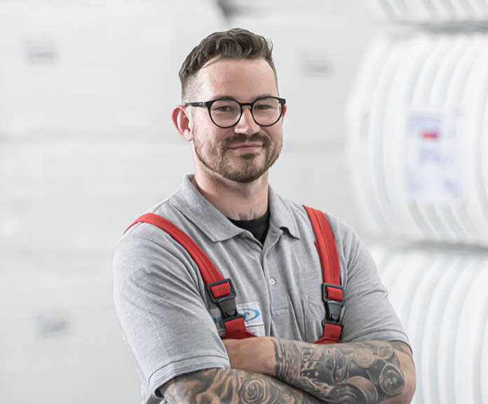 Junger Mitarbeiter mit Brille und roter Latzhose | Sandler Group